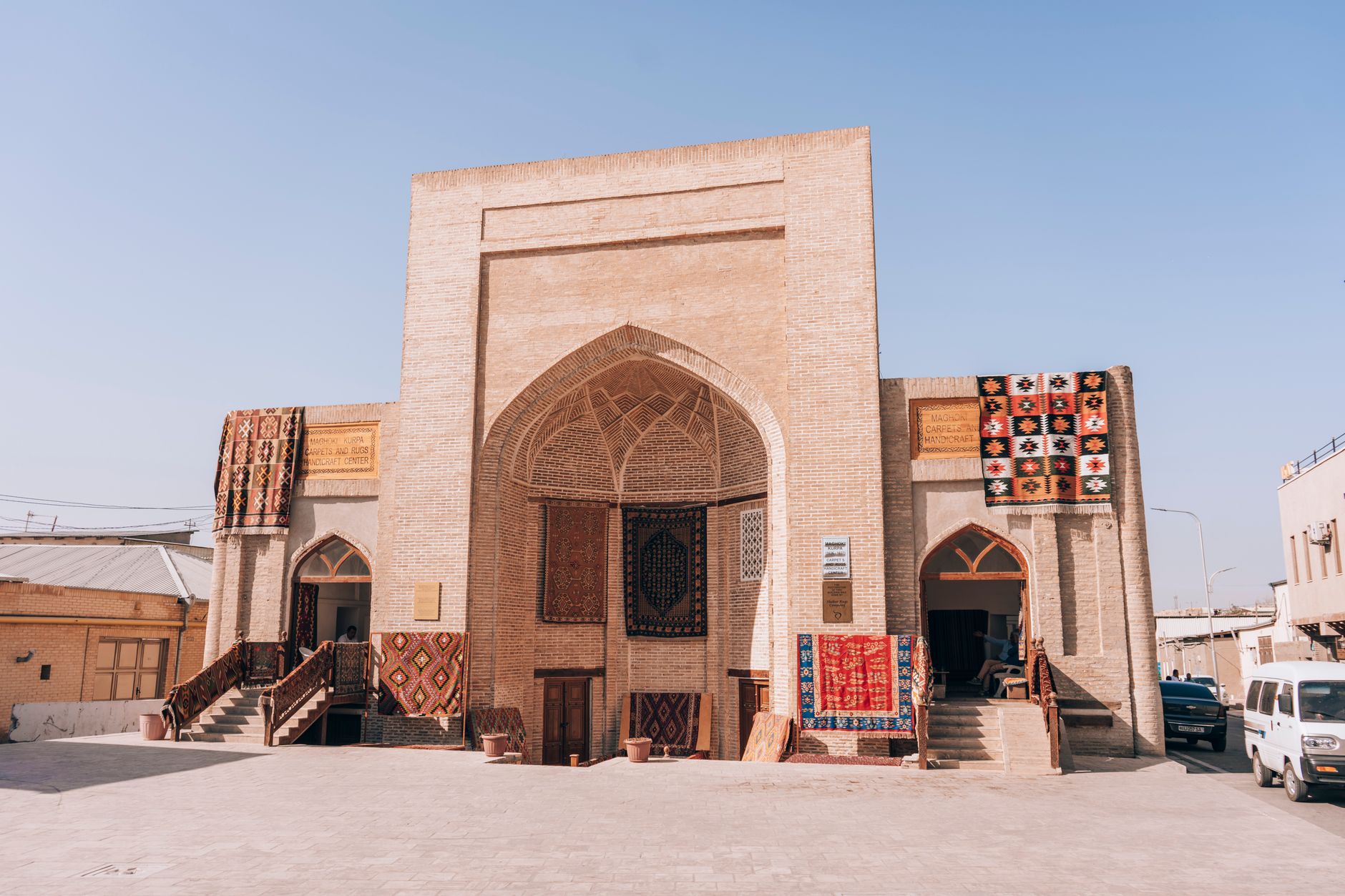 Historic building in Bukhara showcasing Uzbek carpets and textiles under a clear sky · Cities & places, Uzbekistan