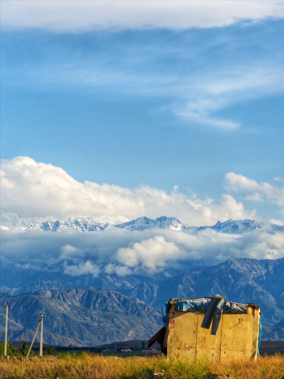 Idyllic view of Uzbek mountains with a hut under a vast blue sky in the Fergana Region · Fergana Valley, Uzbekistan