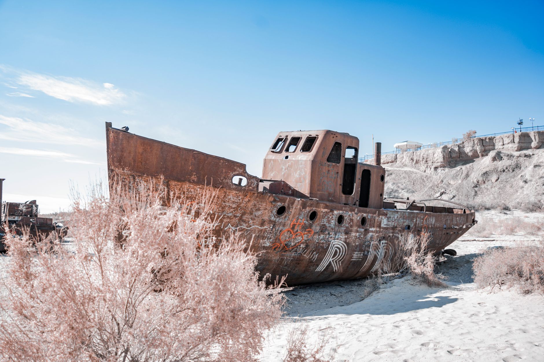 An abandoned rusted ship lies in the barren desert landscape of the Aral Sea, Uzbekistan · Muynak & the Aral Sea, Uzbekistan