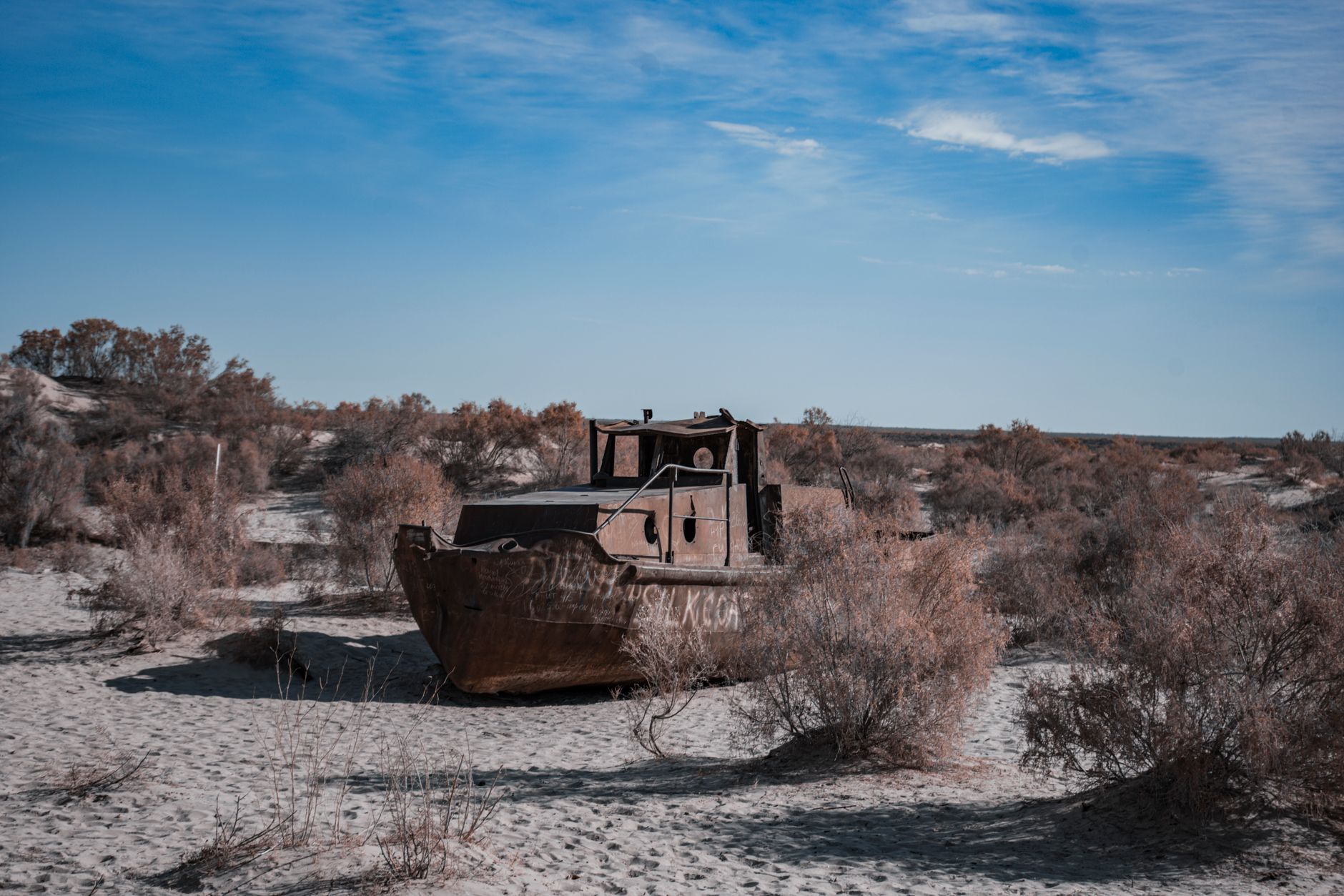 An old, rusting ship stranded on the desert sands of the Aral Sea under a bright blue sky · Muynak & the Aral Sea, Uzbekistan