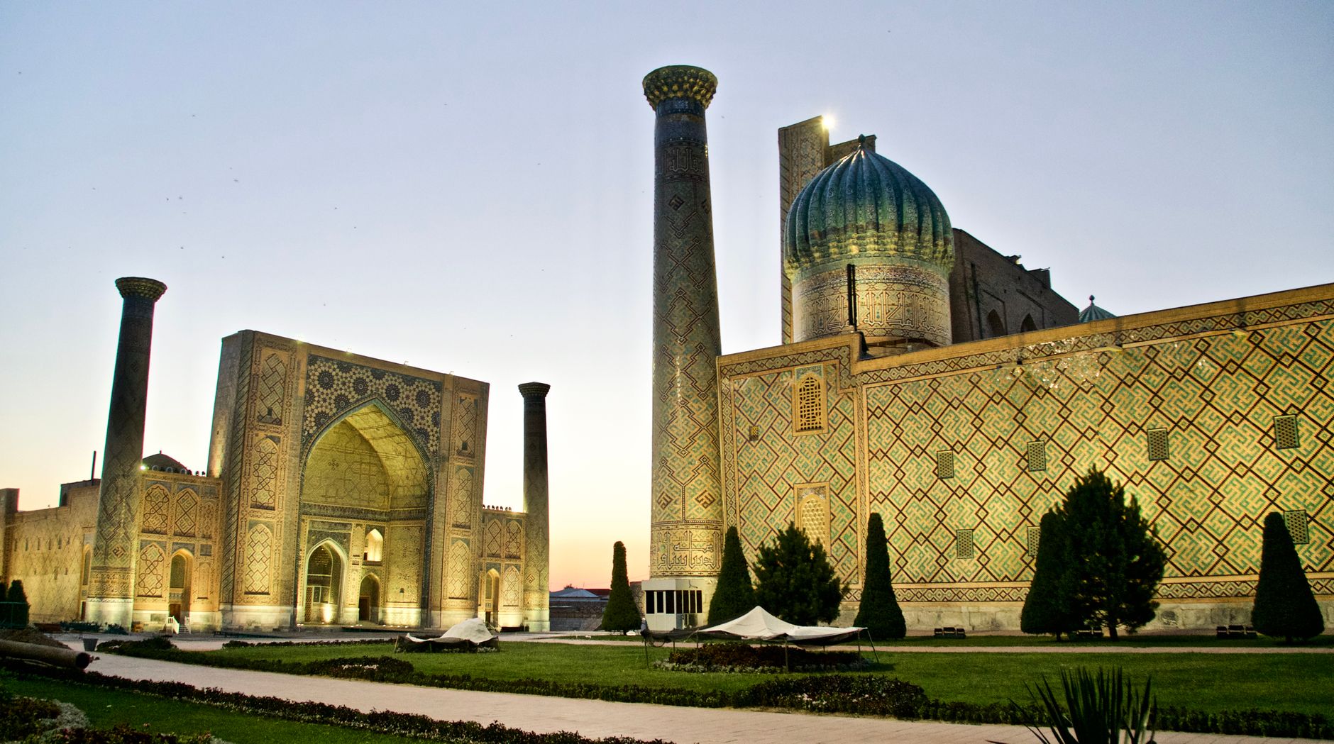 The illuminated Registan complex in Samarkand during twilight, highlighting its intricate architecture, Uzbekistan
