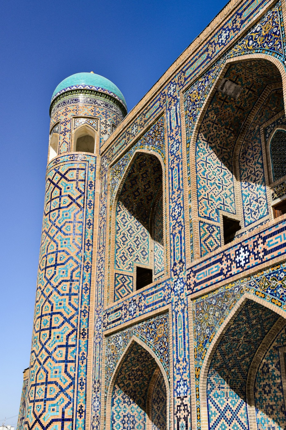 Tilya-Kori Madrasa corner minaret with turquoise dome and dense majolica tilework on the Registan, Samarkand